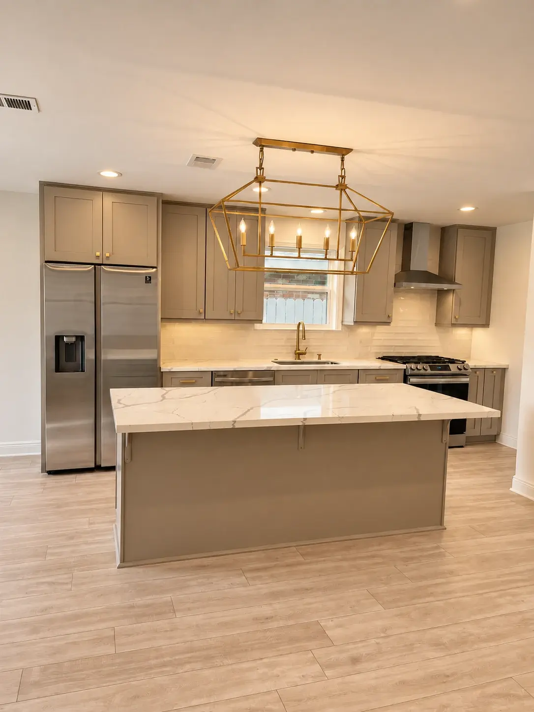 Completed Master Build kitchen with an island, taupe cabinetry and a brass pendant